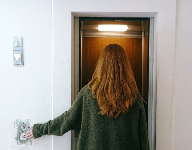 una Mujer de espalda tocando la botonera del ascensor